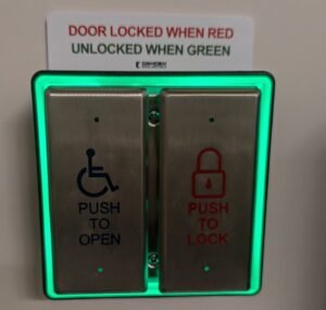Automatic door opener buttons. One says "Push to Open" and the other says "Push to Lock." There is a sign above that says, "Door locked when red, unlocked when green."