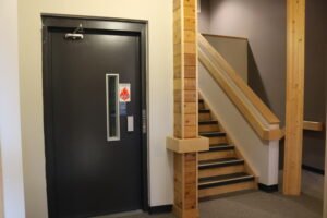 An elevator door beside a set of stairs.