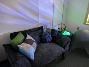 An oversized chair with sensory pillows, sensory lighting and a ball chair.