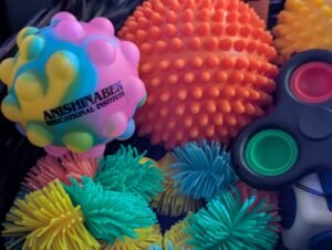 a basket filled with colourful sensory toys. One push pop ball reads ' Anishinabek Educational Institute'